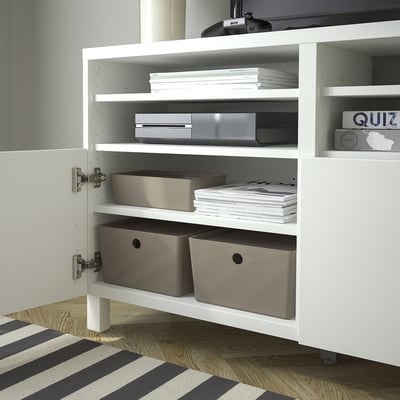 Wit kabinet met open deur, met georganiseerde planken. Inclusief grijze dozen, stapels papieren en elektronische items.