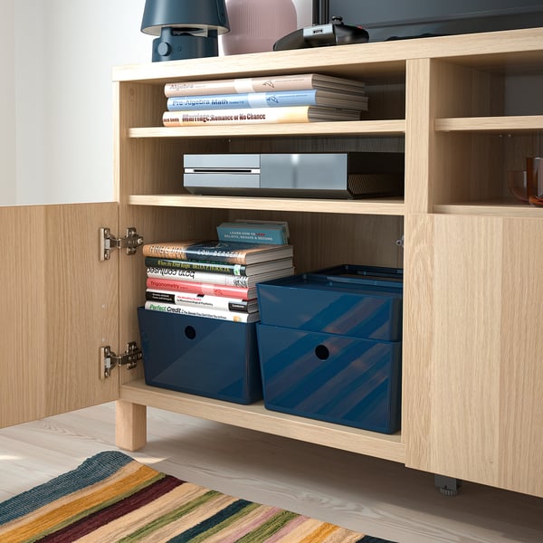 Open houten kast met blauwe plastic opbergdozen en gestapelde boeken, ideaal om spullen te organiseren en op te bergen.