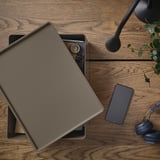 Houten bureau met gesloten laptop, smartphone, koptelefoon en kleine plant. Ideaal voor werken op afstand.