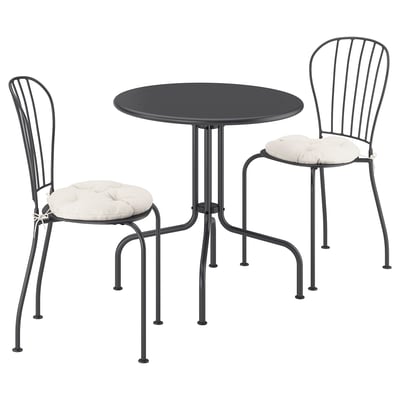 Zwarte ronde buitentafel en twee stoelen met witte kussenzittingen, metalen frame met lattenrugleuningen.