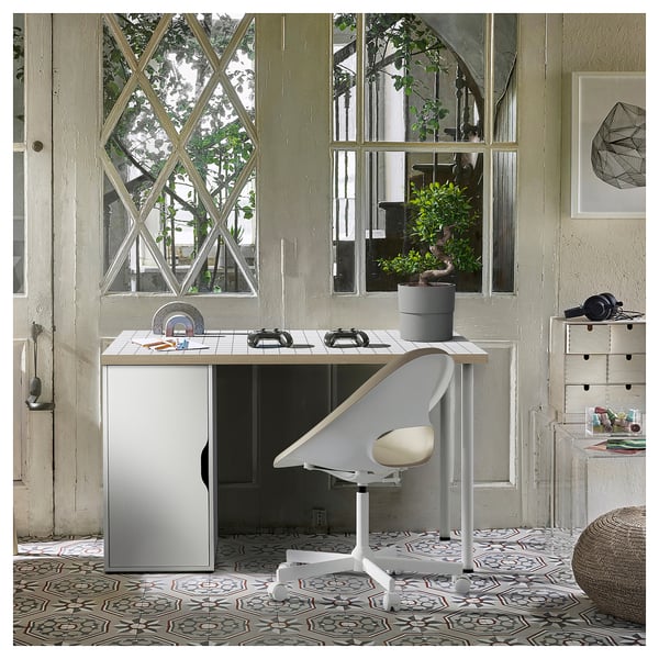 Modern thuiskantoor met LAGKAPTEN-bureau, witte stoel, geometrische tegelvloer. Groot raam met planten.