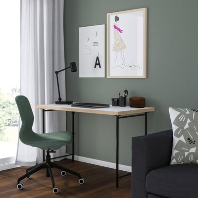 Thuiskantoor met LAGKAPTEN-bureau, groenblauwe stoel, grijze bank, schilderijen, lamp en benodigdheden.