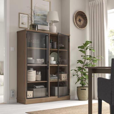 Een houten LANESUND kast met glazen deuren. Het is bruin, rechthoekig en heeft meerdere planken aan de binnenkant.