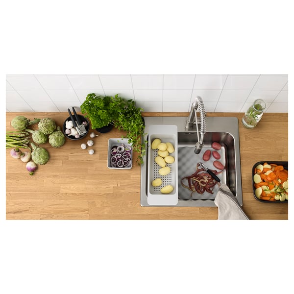 Bovenaanzicht van een houten aanrechtblad in de keuken met roestvrijstalen gootsteen; Diverse groenten en keukengerei netjes gerangschikt.