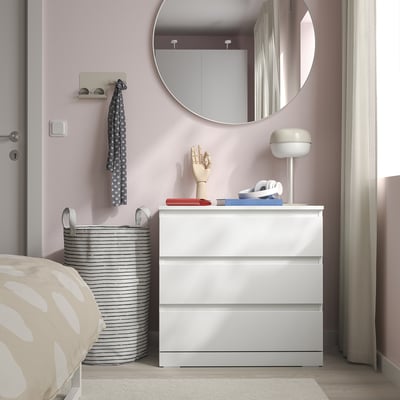Witte kist met drie laden naast bed, onder de ronde spiegel, met gemakkelijk toegankelijke handgrepen