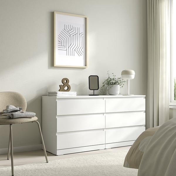 Witte LILLBERGET 6-lades kist met een kunstprint erboven, stoel links, lamp, plant bovenop.