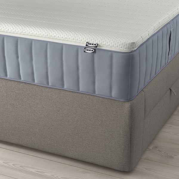 Hoek van een LILLFJÄLLET boxspringbed met schuin hoofdeinde, verwijderbare kussens en opbergruimte onder het bed.