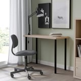 Houten LINNMON bureau met zwarte poten, grijze draaistoel, twee kunstwerken, boekenplank en groot raam met doorschijnende gordijnen.
