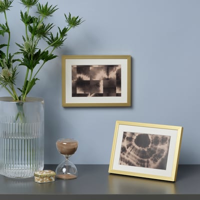 Goud-ingelijste display met twee sepia afbeeldingen, planten en zandloper.