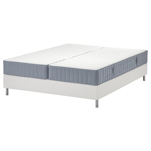 De witte LYNGÖR bedbodem met een grijze valevåg matras. De bedbodem heeft platte latten en de matrasveren en comfortzones.