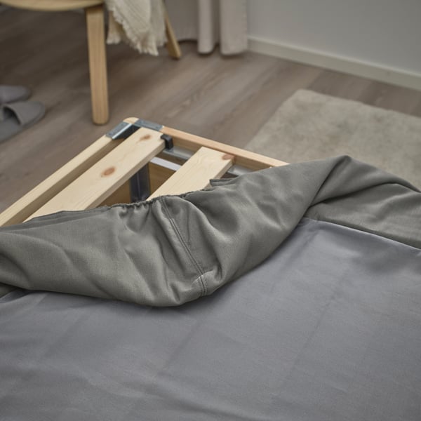 Houten bedframe met grijs hoeslaken, met elastische hoeken.