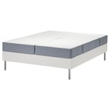 De witte LYNGÖR bedbodem met een blauwgrijze vesteröy matras. Vier metalen poten ondersteunen de basis en de matraszak veren voor comfort.