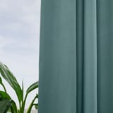 Teal MAJGULL gordijnen verduisteren de kamer, plant voegt leven toe.