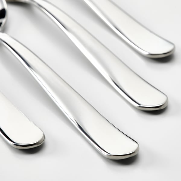 Vier glanzende metalen lepels, schoon en gepolijst, parallel gelegd op een wit oppervlak.