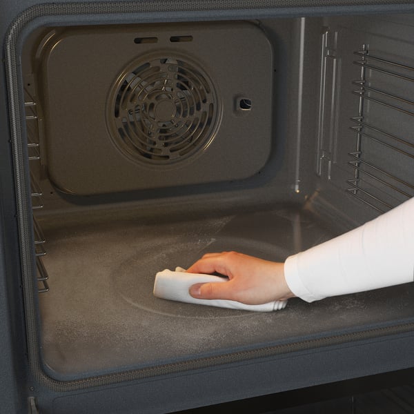 Een oven schoonmaken met een doek.