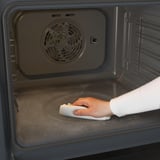 Een oven schoonmaken met een doek.