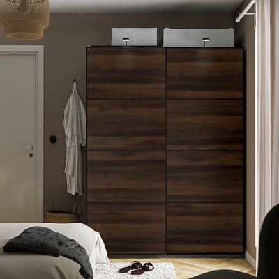 Slaapkamer met een grote donkerbruine MEHAMN-kledingkast , schuifdeuren, grijs bed, hangende kleding, mand.