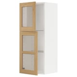 Een witte METOD keukenkast met met eiken beklede glazen deuren, voorzien van verstelbare planken en afgeschuinde randen.