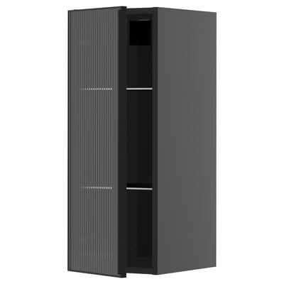 Een zwarte moderne keukenkast met een glazen deur met een metalen frame en verticaal rietontwerp, onderdeel van het METOD-systeem.