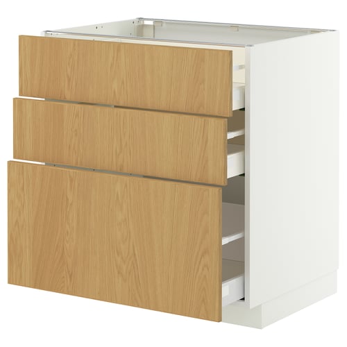 Een witte METOD keukenkast met drie eikenhouten lades. De lades zijn gedeeltelijk open en onthullen opbergvakken.