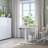 Modern kantoor: wit MITTZON zit/sta bureau bij het raam, tussen kasten en stoel. Licht houten blad, metalen basis, planten & computer.