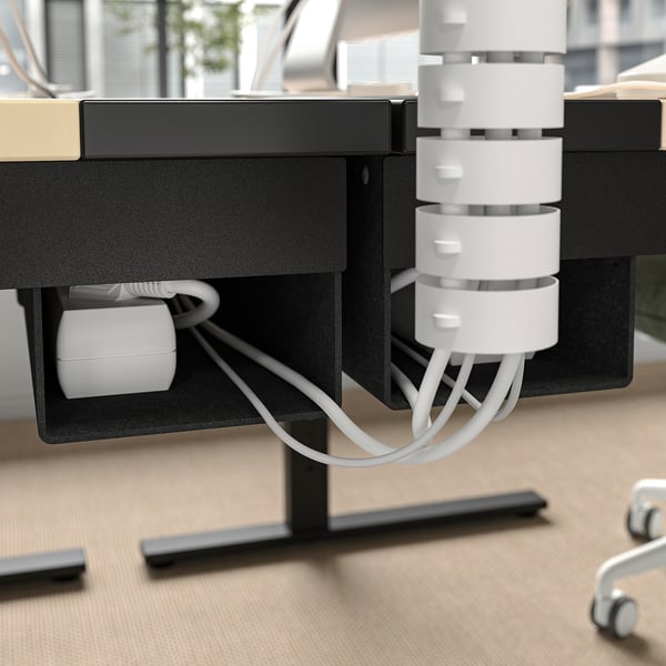 Bureau met kabelgoot en voedingsmodule, met georganiseerde werkruimte voor computergebruik.