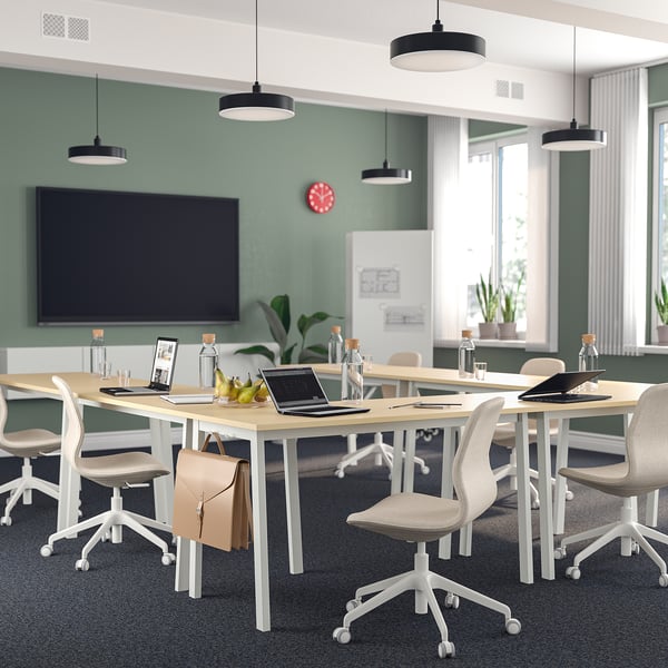 MITTZON vergadertafel, licht hout, modern. Rechthoekig, ruim, biedt plaats aan 10+ stoelen. Gelegen in een ontmoetingsruimte met technologie en planten.