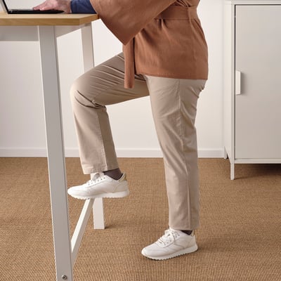 Persoon die zich aan hoge lijst met geïntegreerde voetsteunen bevinden, die ergonomisch zitten of staand werken bevorderen.