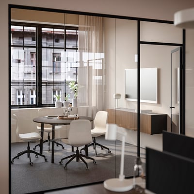 Klein modern kantoor met ronde tafel en vier stoelen, met uitzicht op grote ramen, geschikt voor kleine groepsdiscussies.