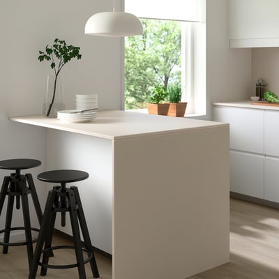 Modern kookeiland met wit MÖCKLARP porseleinen blad, zwarte krukken, borden en groen.
