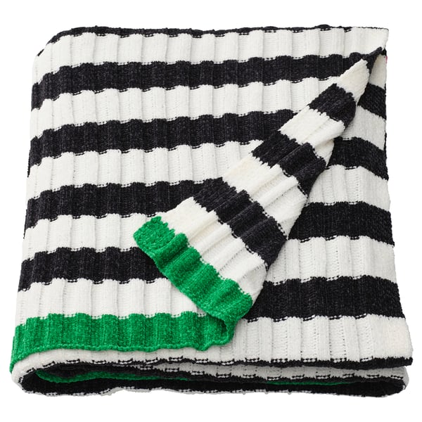Een MOSSMOTT deken met zwart-witte strepen en groene accenten, gemaakt van gerecycled polyester.