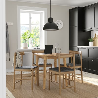 Moderne keuken met NACKANÄS houten eethoek, zwarte hanglamp, grijze radiator en potplant.