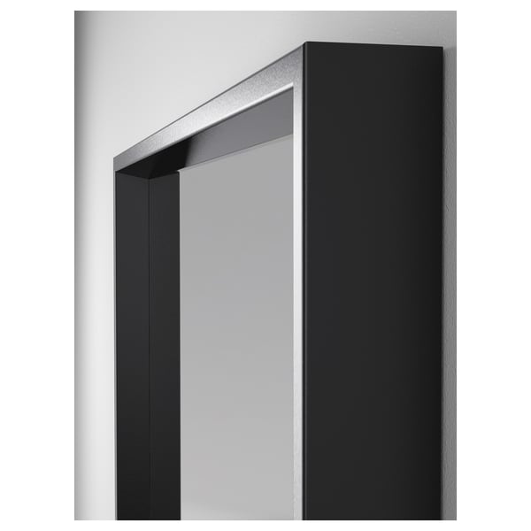 Wandspiegel met zwarte lijst en reflecterend oppervlak en metalen bevestigingen.