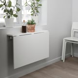 Neerklapbare wandtafel met planten en fles erop.