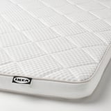 Matrashoek met ikea-label, met zachte witte stof en ruitpatroon, met de nadruk op comfort en kwaliteit.