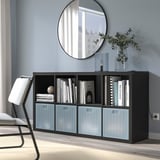 Moderne zwarte boekenplank met blauwe dozen, decoratieve artikelen, spiegel, planten en stoel.