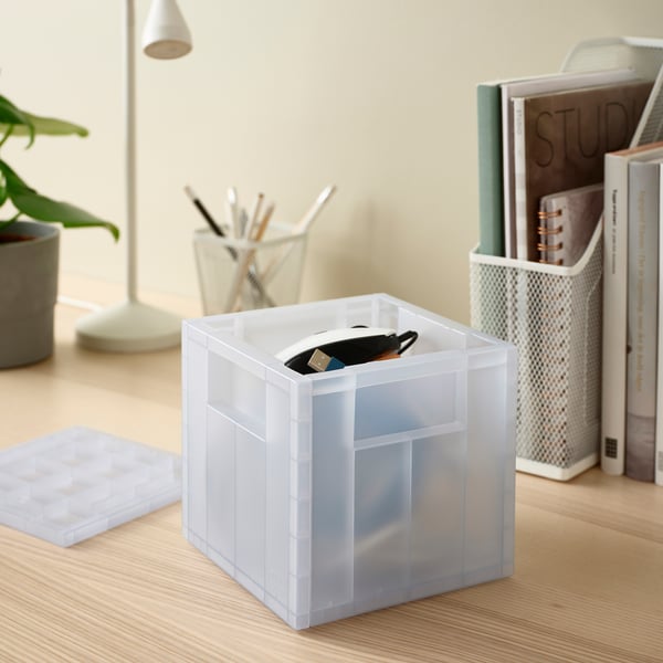 Een PANSARTAX plastic doos op een bureau, met daarin een portemonnee. Het is klein, helder en gedeeltelijk gerecycled, geschikt voor het organiseren van kleine voorwerpen.