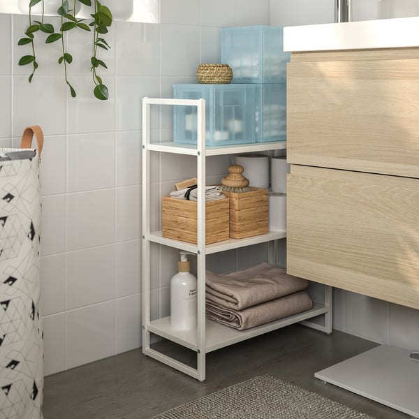 Badkamer met betegelde wand, metalen plank met manden en handdoeken, houten ijdelheid, hangplant.