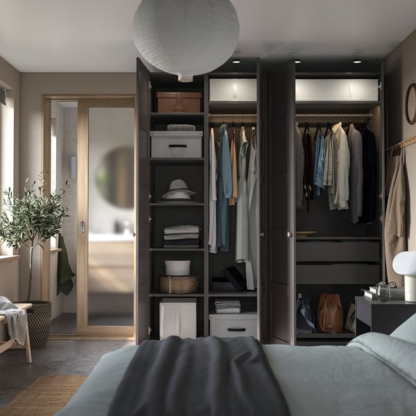 Slaapkamer met zwarte PAX kasten, kleding, bed, lamp.