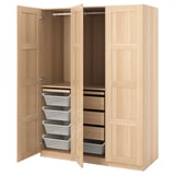 Een houten PAX kledingkast in witte beits, met open deuren die lades, planken en manden binnenin onthullen.