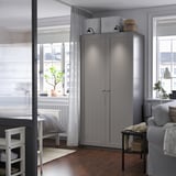 Moderne woonkamer met hoge grijze PAX kledingkast, die ruimte en design verbetert.
