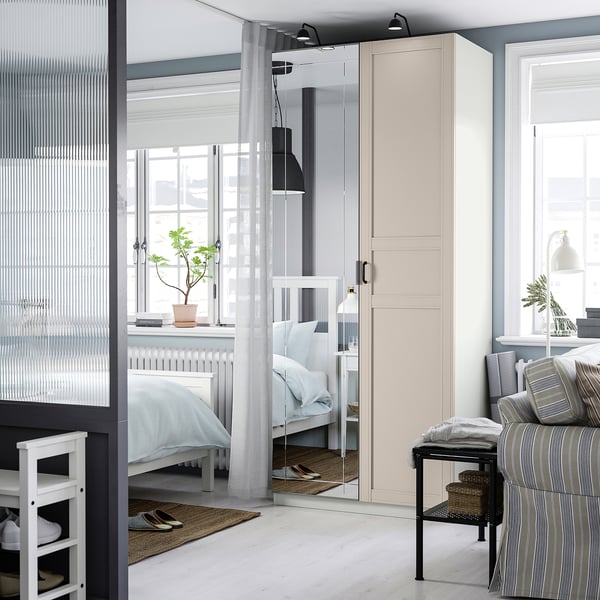 Moderne slaapkamer met PAX kledingkast, spiegeldeuren en gestreepte kussens.