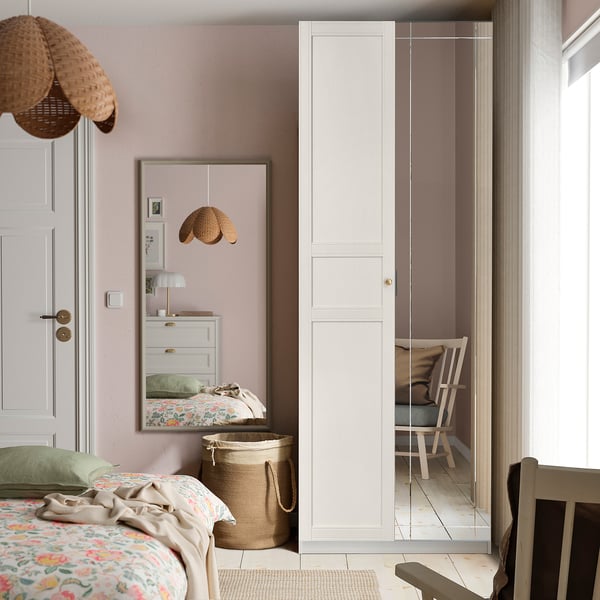 Witte PAX-garderobe in een gezellige slaapkamer, hoog, strak naast het raam, met bloembeddengoed en getextureerde lampen.