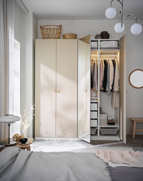 Open lichtbeige PAX kledingkast met kleding en opbergruimte.