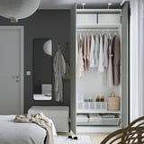 Moderne slaapkamer met PAX kledingkast, spiegel, bed en stoel.