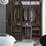 Een open kledingkast met hangende kleding, opgevouwen truien en schoenen, met georganiseerde opslag met planken en ophangsecties.
