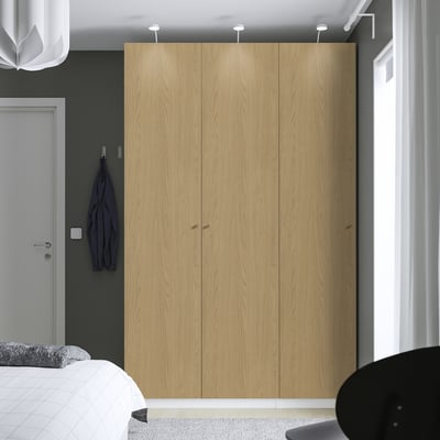 Moderne slaapkamer met grote houten PAX kledingkast, wit bed en blauw kledingstuk.