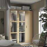 PAX kledingkast: modern ontwerp van hout en glas, hoog, past naast het bed, met hangende kledingruimte, natuurlijk licht uit het raam.