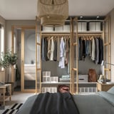 Moderne kledingkast met hangende kleding, planken en een stijlvolle hanglamp. Onderdeel van een georganiseerde slaapkamersuite.