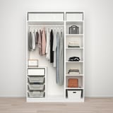 Een witte kledingkast PAX met hangende kleding, opgevouwen items, manden en accessoires netjes georganiseerd.